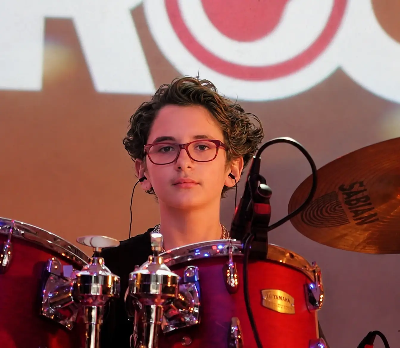Leonidas Cantrell seated behind a red drum kit, wearing glasses.