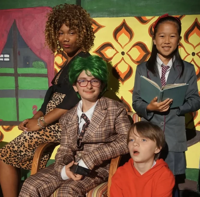 Leonidas Cantrell in a plaid suit and green wig with fellow performers on a colorful stage.